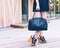 Fashion. A girl in a black dress and with a fashionable handbag is standing on the veranda of a summer cafe