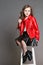 Fashion Girl in a red jacket poses and grimaces and makes a face. Photo Studio on a gray background. Birthday, holiday