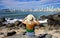 Fashion girl sitting on the rocks looking at Balneario Camboriu city skyline on Atlantic Ocean, Santa Catarina, Southern Brazil