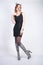 Fashion girl wearing black little dress from spandex with zebra velvet boots with high heels on white studio background