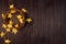 Fashion glittering festive decoration - wreath with golden glowing stars on dark brown wood board, border, top view.