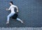 Fashion guy jumping against black brick wall with purchases, shopping