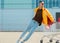 Fashion guy in sunglasses and a yellow jacket sits in a cart from food in the supermarket parking