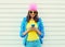 Fashion happy cool smiling girl using smartphone in colorful clothes over white background wearing pink hat yellow sunglasses