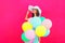 Fashion happy pretty smiling woman with an air colorful balloons is having fun in summer over a pink background