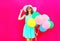 Fashion happy pretty smiling woman with an air colorful balloons is having fun wearing a summer straw hat over a pink background