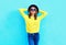 Fashion happy pretty smiling woman wearing a black hat and yellow knitted sweater over colorful blue