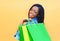 Fashion happy smiling african woman with shopping bags in city over orange background