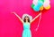 Fashion happy smiling woman with an air colorful balloons is having fun in summer over a pink background