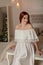 Fashion interior portrait of beautiful young woman and evening makeup, wears evening white dress. Vogue style model girl in elegan