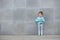 Fashion kid posing near gray wall