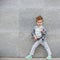 Fashion kid posing near gray wall