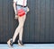 Fashion leggy girl in a beautiful high-heeled shoes in short denim shorts summer posing near the dark wall. Close-up