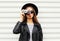 Fashion look, pretty cool young woman model with retro film camera wearing elegant black hat, leather rock jacket over white