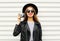 Fashion look, pretty young woman model with retro film camera wearing elegant black hat, leather rock jacket over white