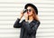 Fashion look, pretty young woman model with retro film camera wearing elegant hat, leather rock jacket over white