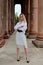 Fashion look`s woman. Young woman modern portrait. Young woman dressed in white skirt and shirt posing near the old building.