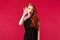 Fashion, luxury and beauty concept. Portrait of curious gossiping young redhead woman in black dress, makeup, hold hand