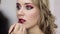 Fashion makeup artist applying burgundy lip gloss