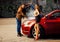 Fashion male model reparing car for voluptuous blonde young woma