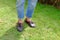 Fashion Man is Legs in Blue Jeans and Wear Vintage Shoes on Green Grass Background
