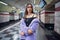 Fashion model girl in purple synthetic fur coat standing bared her shoulders in the walking subway passage platform