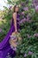 Fashion Model in Lilac Flowers, Young Woman in Beautiful Long Dress Waving on Wind, Outdoor Beauty Portrait in Blooming