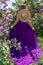 Fashion Model in Lilac Flowers, Young Woman in Beautiful Long Dress Waving on Wind, Outdoor Beauty Portrait in Blooming