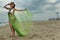 Fashion model woman in design bikini with blowing cover up posing pretty on the beach.