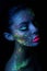 Fashion model woman in neon light bright fluorescent makeup, drop on face. Beautiful model brunette girl colorful make-up, painted