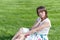 Fashion of nice pretty young hipster woman is sitting on green grass in a blouse and long skirt