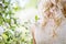 Fashion outdoor photo of beautiful young woman in elegant dress posing in garden with blossom apple trees. Blonde in flowering