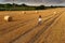 Fashion photo, beautiful woman cycling in a wheat field, a lot of bales of wheat