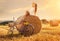 Fashion photo, beautiful woman sitting on a bale of wheat, next to the old bike