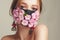 Fashion photo of a girl in a mask of flowers. Spring that we cannot breathe. Virus, pandemic, coronavirus, masked model