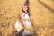 Fashion photo of a little girl in white dress and straw hat at the evening wheat field