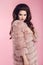 Fashion photo of woman in fur coat over pink studio background.