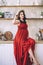 Fashion portrait of attractive stylish pregnant lady in long red sarafan and straw hat, photo of the happy and beautiful