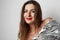 Fashion portrait of a beautiful young woman in a pretty silver dress with tinsel posing over empty light background