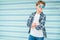 Fashion portrait of caucasian blonde hair 12 year old teenager boy dressed t-shirt and checkered shirt in blue sunglasses posing