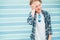 Fashion portrait of caucasian blue-eyed blonde hair 12 year old teenager boy dressed t-shirt and checkered shirt with sunglasses