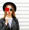 Fashion portrait face pretty sweet young woman with red lips making air kiss with lollipop heart wearing black hat leather jacket