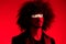 Fashion portrait of a man with curly hair on a red background, multinational, colored light, trendy, modern concept.