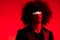 Fashion portrait of a man with curly hair on a red background, multinational, colored light, trendy, modern concept.