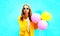 Fashion portrait woman holds balloons sends an air kiss in yellow