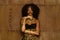 Fashion portrait of young african or black american model wearing gold clothes and makeup, bronze wall background