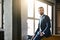 Fashion portrait. Young bearded successful businessman in stylish suit is standing at office and thinking about