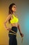 Fashion portrait of young fit and sportive woman with measurer on gradient background. Perfect body ready for summertime