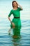 Fashion portrait of a young model with wet long ginger red hair in green emerald dress posing at the seaside. Perfect skin and