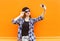 Fashion pretty cool girl makes selfie portrait on smartphone over colorful orange